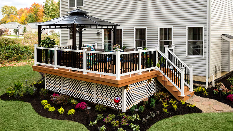 Custom backyard deck with gazebo, white railing, lattice skirt and manicured landscaping, Connecticut carpentry project