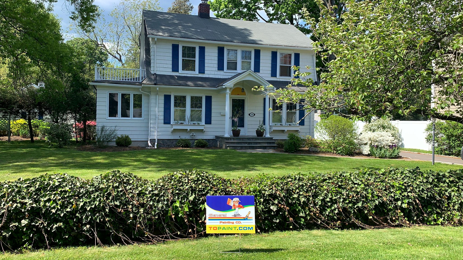Classic Connecticut colonial with blue shutters and General Painting Co. yard sign in the front yard — finished exterior repaint