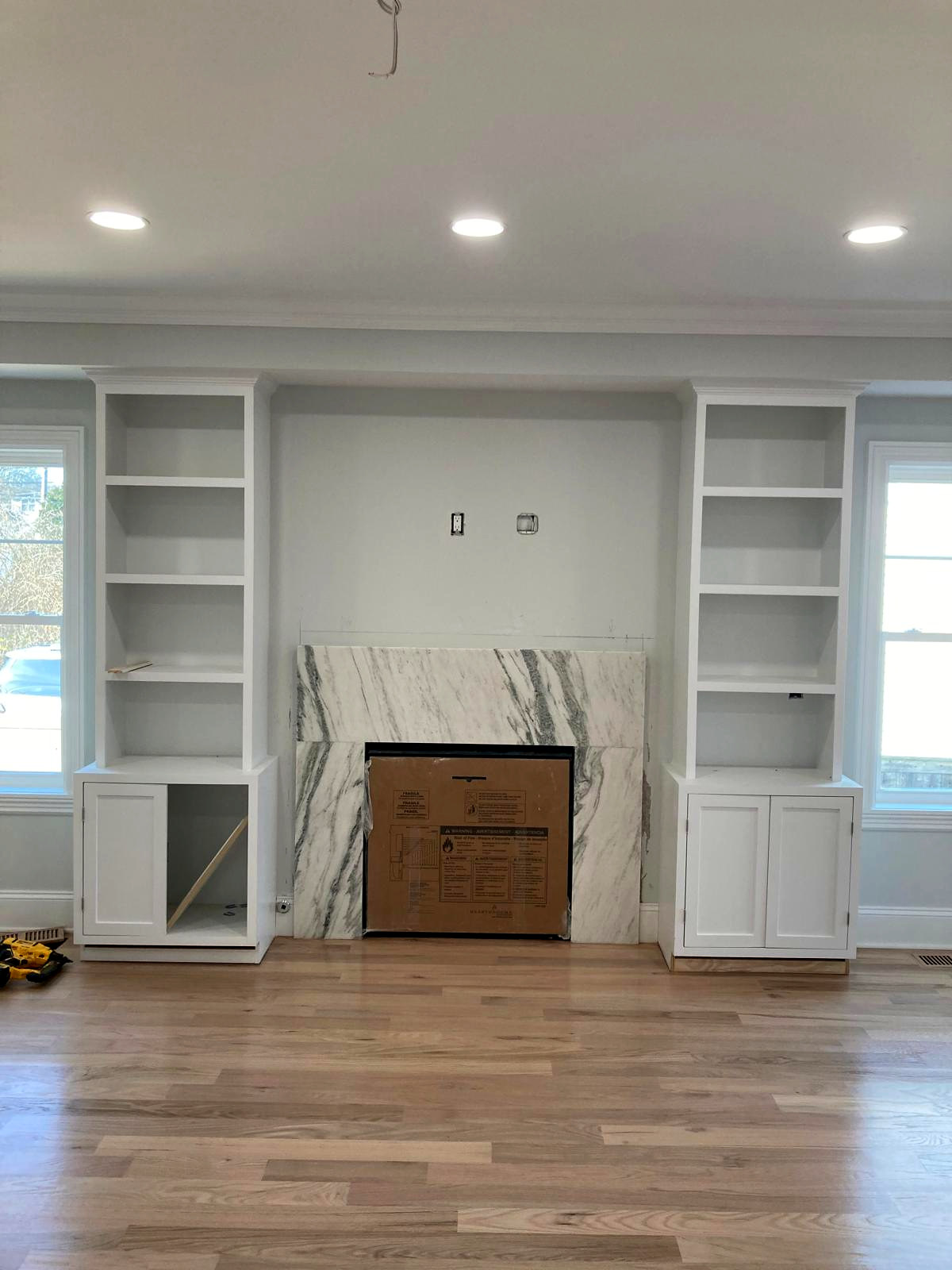Custom white fireplace surround with flanking built-in shelves and marble tile, Connecticut interior project