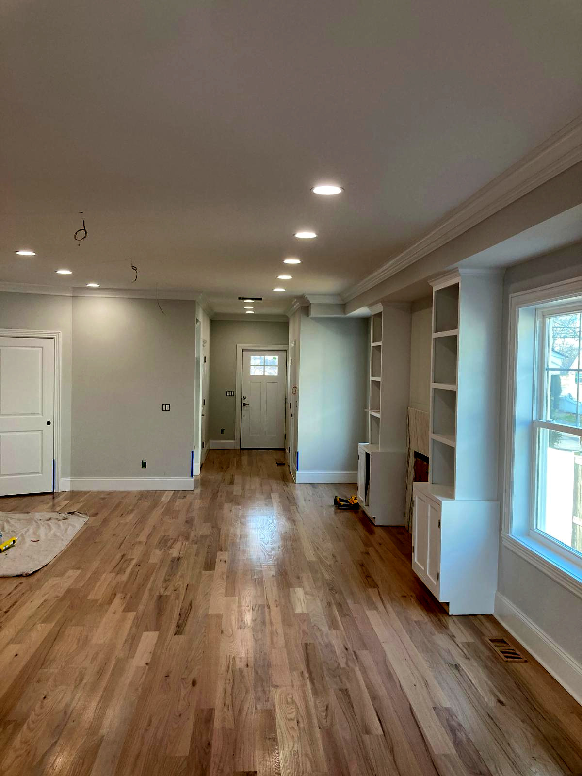 Open-concept living and dining room with soft gray walls, white trim, and built-in shelving — interior painting Connecticut